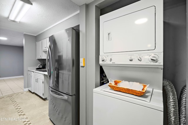 467 Canberra Dr Unit B103, Knoxville, TN 37923 - laundry area featuring stacked washer / dryer, light tile patterned flooring, a textured ceiling, and baseboards