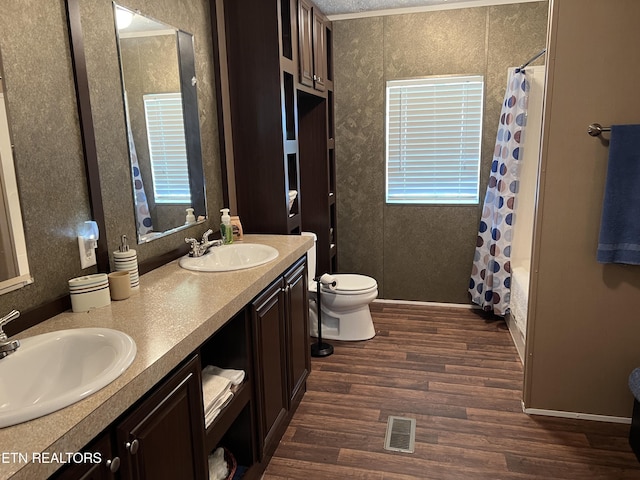 3385 Double Top Rd, Byrdstown, TN 38549 - full bath featuring wood finished floors, toilet, double vanity, wallpapered walls, and shower / tub combo with curtain