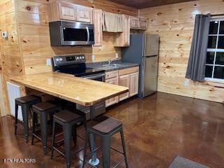138 Matthews Rd, Oneida, TN 37841 - kitchen with appliances with stainless steel finishes, a kitchen breakfast bar, a peninsula, and wooden walls