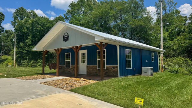138 Matthews Rd, Oneida, TN 37841 - view of front of house with covered porch, a front yard, central air condition unit, stone siding, and board and batten siding