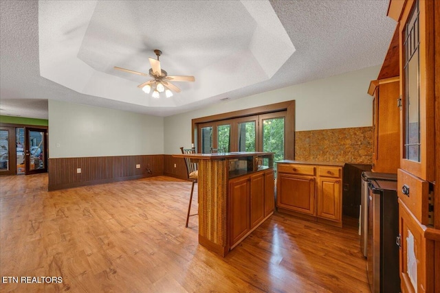158 Dillon Rd, Baxter, TN 38544 - kitchen featuring brown cabinets, a wainscoted wall, a breakfast bar, light wood finished floors, and a peninsula