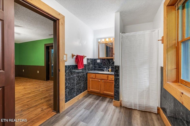158 Dillon Rd, Baxter, TN 38544 - full bathroom with a textured ceiling, wood finished floors, a wainscoted wall, vanity, and a shower with shower curtain