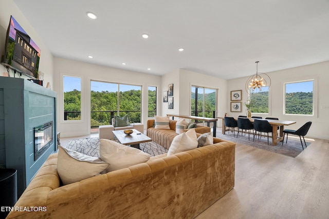2955 Lightning Strike Dr, Sevierville, TN 37862 - living room featuring light wood-style flooring, a chandelier, a glass covered fireplace, recessed lighting, and baseboards