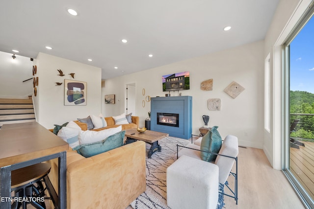 2955 Lightning Strike Dr, Sevierville, TN 37862 - living room featuring light wood-style flooring, a glass covered fireplace, stairs, recessed lighting, and baseboards