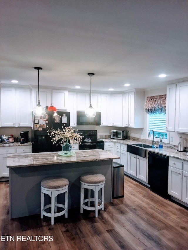 1748 Circle Lake Dr, Dandridge, TN 37725 - kitchen with black appliances, a sink, white cabinetry, a breakfast bar area, and a kitchen island