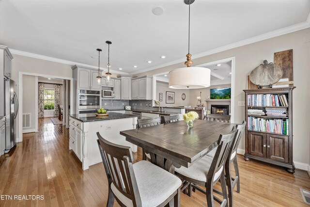12332 Bonnybridge Ln, Knoxville, TN 37922 - dining room with a lit fireplace, light wood-type flooring, ornamental molding, baseboards, and recessed lighting