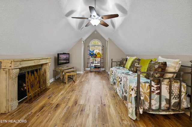 3325 Tekoa Mountain Way, Sevierville, TN 37876 - bedroom featuring vaulted ceiling, wood finished floors, a textured ceiling, baseboards, and a lit fireplace