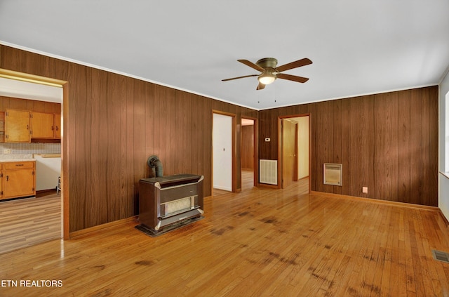 2594 Indian Creek Rd, Thorn Hill, TN 37881 - unfurnished living room with a ceiling fan, a wood stove, heating unit, wooden walls, and light wood-type flooring