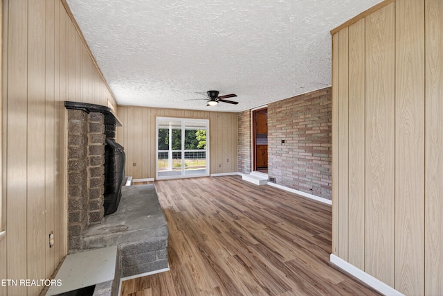 2594 Indian Creek Rd, Thorn Hill, TN 37881 - unfurnished living room with ceiling fan, a wood stove, a textured ceiling, wood finished floors, and wood walls