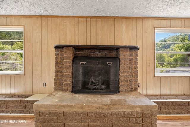 2594 Indian Creek Rd, Thorn Hill, TN 37881 - detailed view of a fireplace with raised hearth, wood walls, a textured ceiling, and wood finished floors