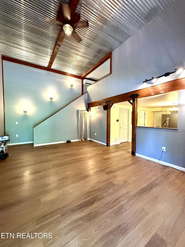179 Wiggins Rd, Tellico Plains, TN 37385 - unfurnished living room featuring ceiling fan, baseboards, wood finished floors, beam ceiling, and high vaulted ceiling