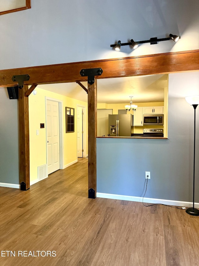 179 Wiggins Rd, Tellico Plains, TN 37385 - unfurnished living room with wood finished floors, baseboards, and a chandelier