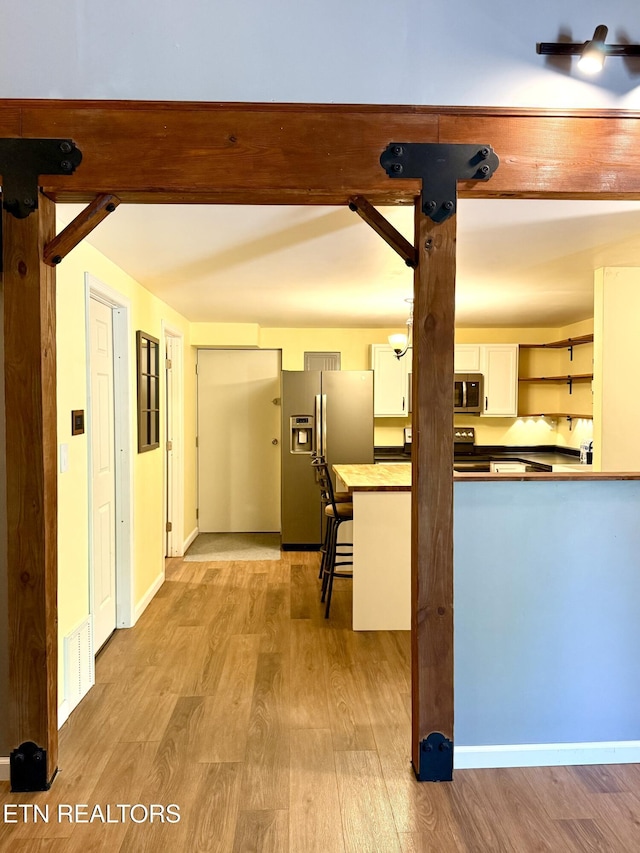 179 Wiggins Rd, Tellico Plains, TN 37385 - kitchen featuring appliances with stainless steel finishes, light wood finished floors, open shelves, white cabinets, and dark countertops