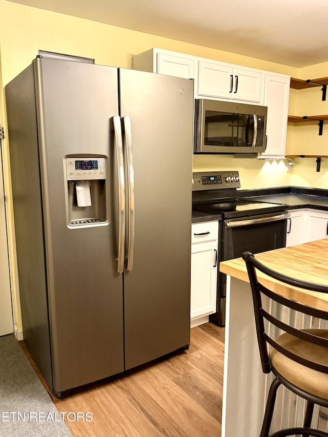 179 Wiggins Rd, Tellico Plains, TN 37385 - kitchen featuring appliances with stainless steel finishes, white cabinets, light wood-style floors, and open shelves