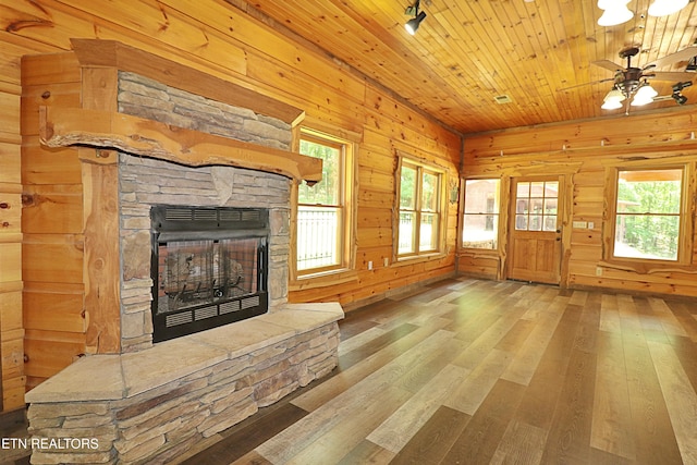 495 Bear Hollow Rd, Oneida, TN 37841 - unfurnished living room featuring a stone fireplace, hardwood / wood-style floors, wooden walls, ceiling fan, and track lighting