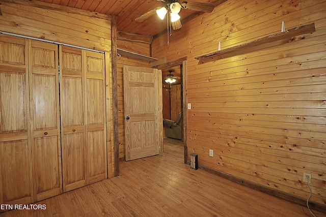 495 Bear Hollow Rd, Oneida, TN 37841 - unfurnished bedroom with wood ceiling, wooden walls, light wood-type flooring, and a closet