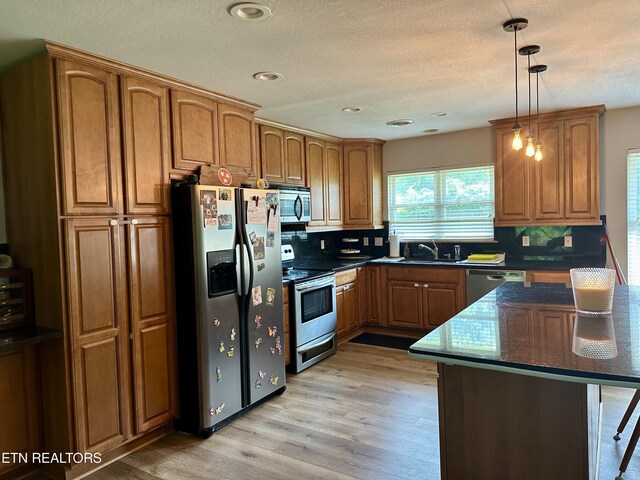 306 E Tri County Blvd, Oliver Springs, TN 37840 - kitchen with stainless steel appliances, brown cabinetry, light wood-style floors, backsplash, and hanging light fixtures