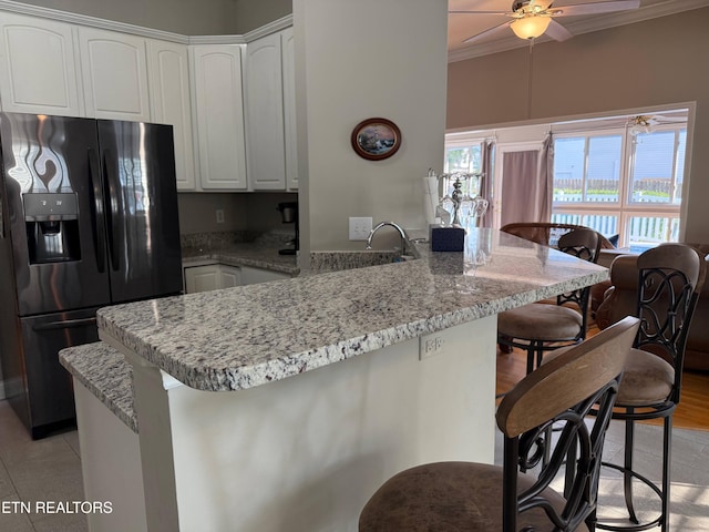 7243 Autumn View Ln, Powell, TN 37849 - kitchen with black fridge, a peninsula, crown molding, a breakfast bar area, and a ceiling fan