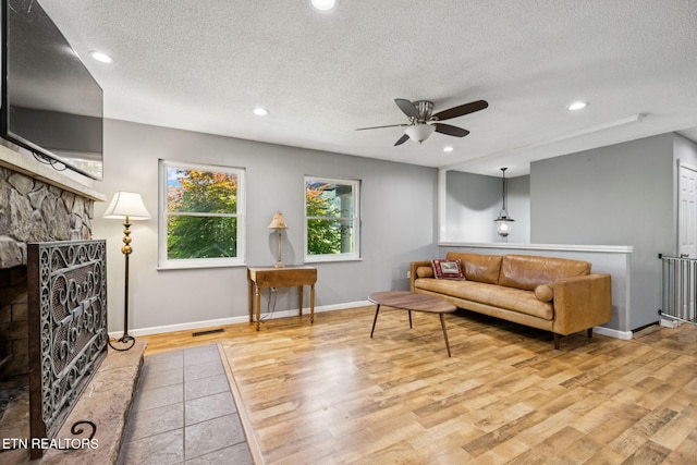 7901 Ewing Rd, Powell, TN 37849 - living area featuring ceiling fan, a textured ceiling, a fireplace, wood finished floors, and baseboards