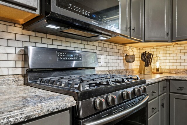 7901 Ewing Rd, Powell, TN 37849 - kitchen with stainless steel appliances, gray cabinetry, backsplash, and light stone counters