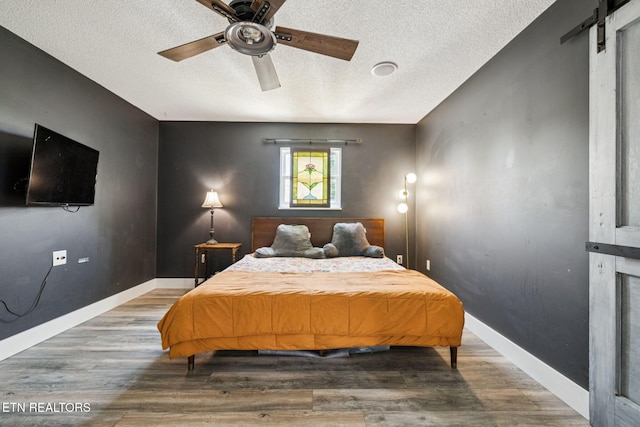 7901 Ewing Rd, Powell, TN 37849 - bedroom with a textured ceiling, wood finished floors, baseboards, a barn door, and a ceiling fan