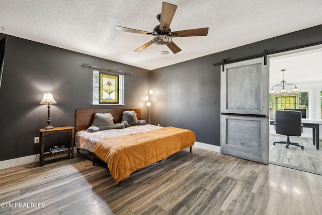 7901 Ewing Rd, Powell, TN 37849 - bedroom with wood finished floors, a textured ceiling, a barn door, multiple windows, and baseboards