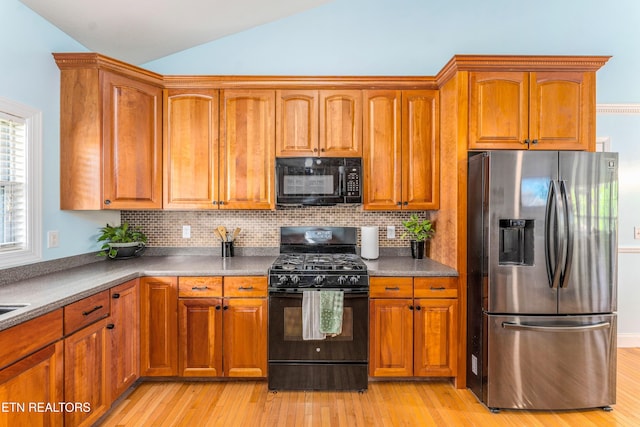 7924 Cedar Stone Ln, Powell, TN 37849 - kitchen with black appliances, lofted ceiling, brown cabinets, and light wood-type flooring