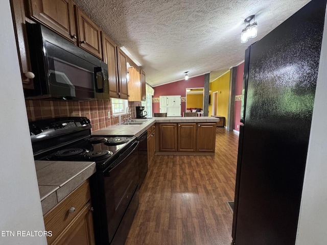 108 Hawn Dr, Crab Orchard, TN 37723 - kitchen featuring black appliances, a peninsula, dark wood-style floors, a textured ceiling, and lofted ceiling