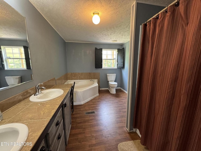 108 Hawn Dr, Crab Orchard, TN 37723 - full bathroom featuring a textured ceiling, toilet, a garden tub, double vanity, and wood finished floors