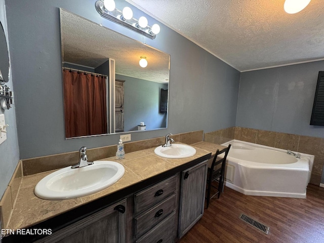 108 Hawn Dr, Crab Orchard, TN 37723 - bathroom featuring a textured ceiling, wood finished floors, double vanity, and a bath