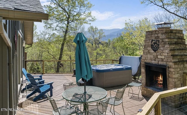 725 Sunshine Trl, Gatlinburg, TN 37738 - deck with a lit fireplace, a hot tub, a mountain view, outdoor dining area, and a patio area