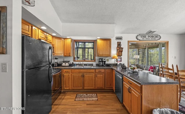 725 Sunshine Trl, Gatlinburg, TN 37738 - kitchen featuring black appliances, a peninsula, dark wood-type flooring, a textured ceiling, and dark countertops