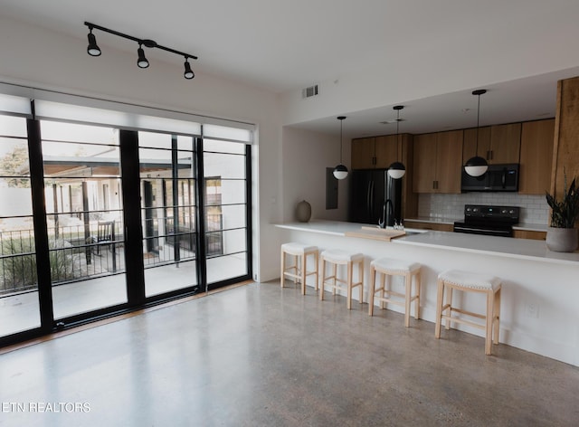 3415 N Broadway St Unit 105, Knoxville, TN 37917 - kitchen featuring black appliances, a peninsula, backsplash, a kitchen breakfast bar, and light countertops