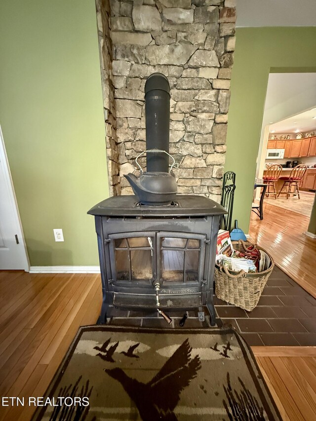 406 Asheville Hwy, Strawberry Plains, TN 37871 - detailed view of a wood stove, wood finished floors, white microwave, and baseboards