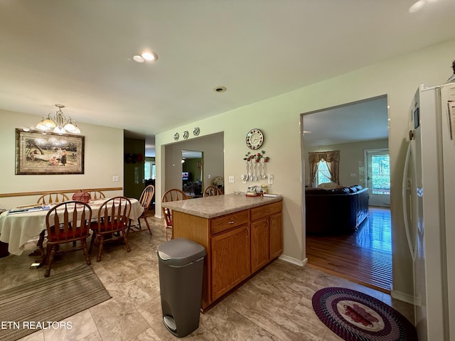 406 Asheville Hwy, Strawberry Plains, TN 37871 - kitchen with freestanding refrigerator, brown cabinetry, a chandelier, pendant lighting, and a peninsula