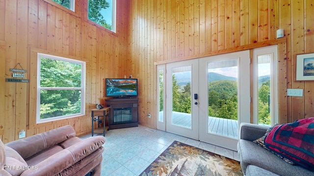 1464 Blue Mill Rd, Del Rio, TN 37727 - living area featuring a high ceiling, wooden walls, a glass covered fireplace, tile patterned flooring, and plenty of natural light