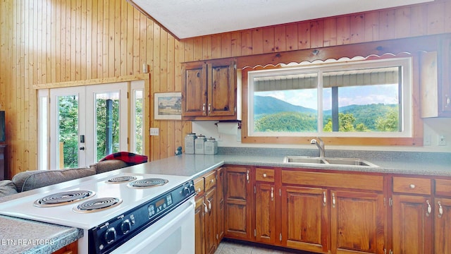 1464 Blue Mill Rd, Del Rio, TN 37727 - kitchen with white range with electric stovetop, a sink, wooden walls, brown cabinets, and light countertops