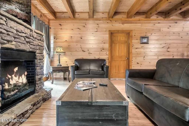 1056 Black Bear Cub Way, Sevierville, TN 37862 - living area with wood ceiling with exposed beams, light wood-style floors, a stone fireplace, and wood walls