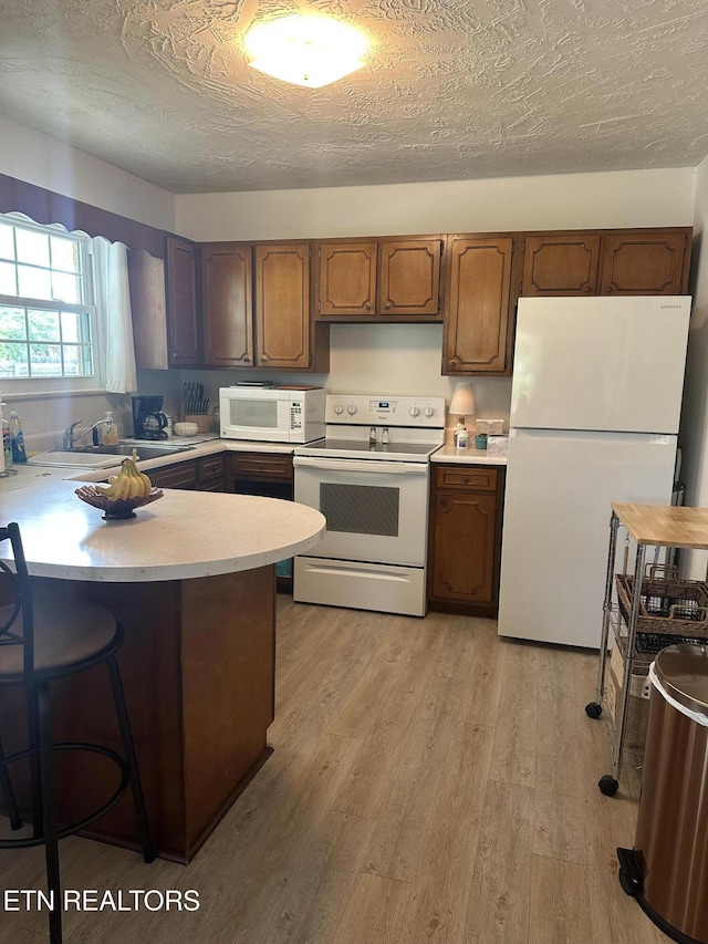 2605 Mountain View Dr, Morristown, TN 37814 - kitchen with white appliances, light countertops, a peninsula, light wood finished floors, and a kitchen bar