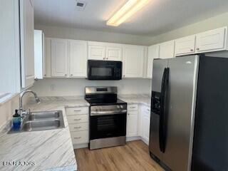 6206 Jim Fox Ln, Powell, TN 37849 - kitchen featuring stainless steel appliances, a sink, white cabinetry, light countertops, and light wood-style floors
