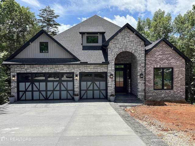 104 Noya Ln, Loudon, TN 37774 - view of front facade featuring concrete driveway, a garage, stone siding, roof with shingles, and board and batten siding
