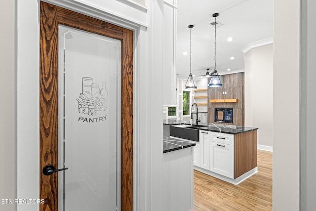 104 Noya Ln, Loudon, TN 37774 - kitchen featuring dark countertops, light wood-type flooring, white cabinetry, a sink, and decorative light fixtures