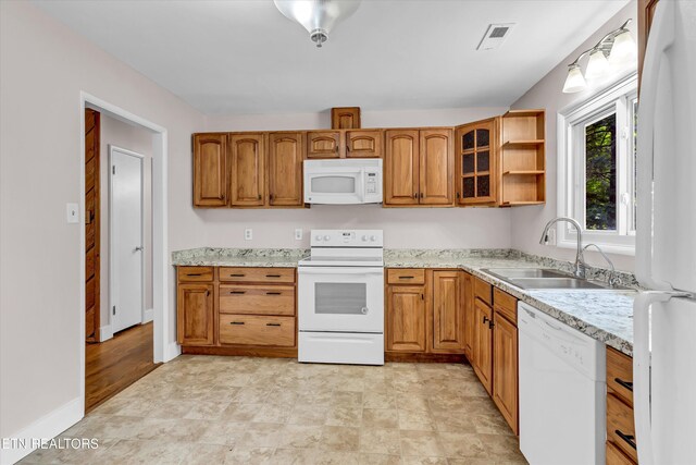9209 Topoco Dr, Knoxville, TN 37922 - kitchen with white appliances, brown cabinetry, glass insert cabinets, and light stone countertops