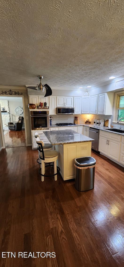 1922 Chaney Ridge Rd, London, KY 40741 - kitchen with stainless steel appliances, a sink, dark wood finished floors, a center island, and a textured ceiling