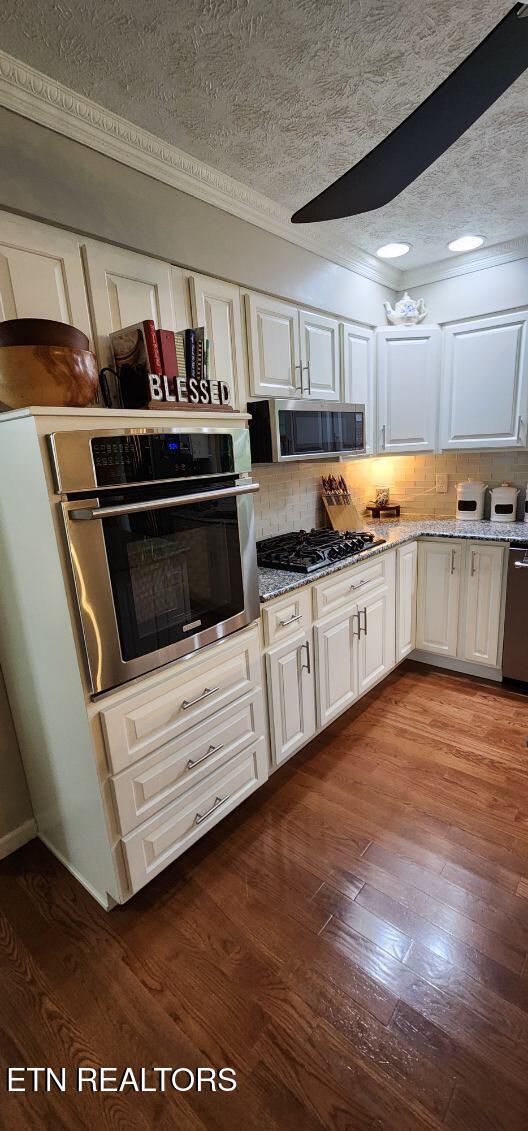 1922 Chaney Ridge Rd, London, KY 40741 - kitchen with stainless steel appliances, decorative backsplash, a textured ceiling, dark wood finished floors, and white cabinets