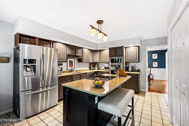 10513 River Ridge Rd, Knoxville, TN 37922 - kitchen featuring appliances with stainless steel finishes, light tile patterned floors, dark brown cabinetry, a center island, and pendant lighting