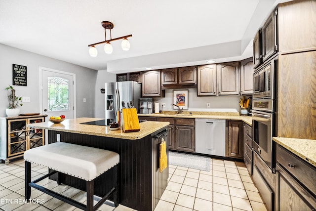 10513 River Ridge Rd, Knoxville, TN 37922 - kitchen with appliances with stainless steel finishes, light tile patterned flooring, a center island, a kitchen breakfast bar, and dark brown cabinetry
