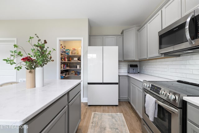 8104 Equinox Ln, Powell, TN 37849 - kitchen featuring stainless steel appliances, gray cabinets, tasteful backsplash, light wood-style flooring, and light stone countertops
