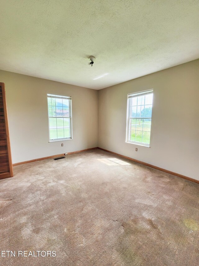 232 Kimberly Rd, Lafollette, TN 37766 - unfurnished room with plenty of natural light, carpet floors, baseboards, a heating unit, and a textured ceiling