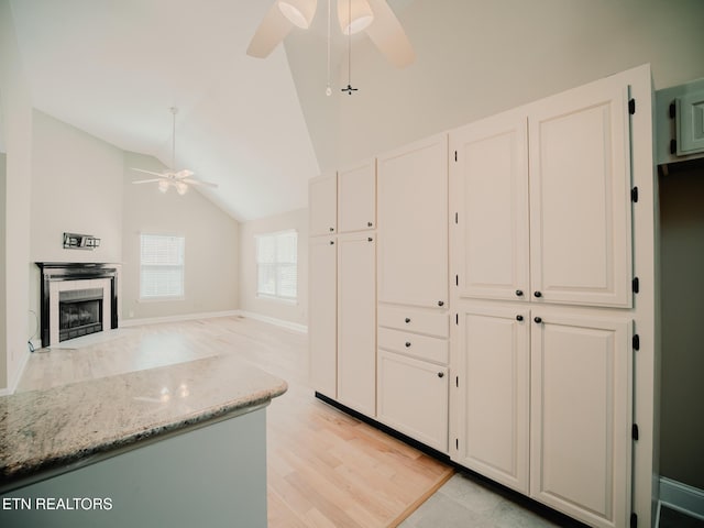 116 Deer Path Trl, Vonore, TN 37885 - kitchen with ceiling fan, light stone counters, white cabinets, vaulted ceiling, and a tile fireplace